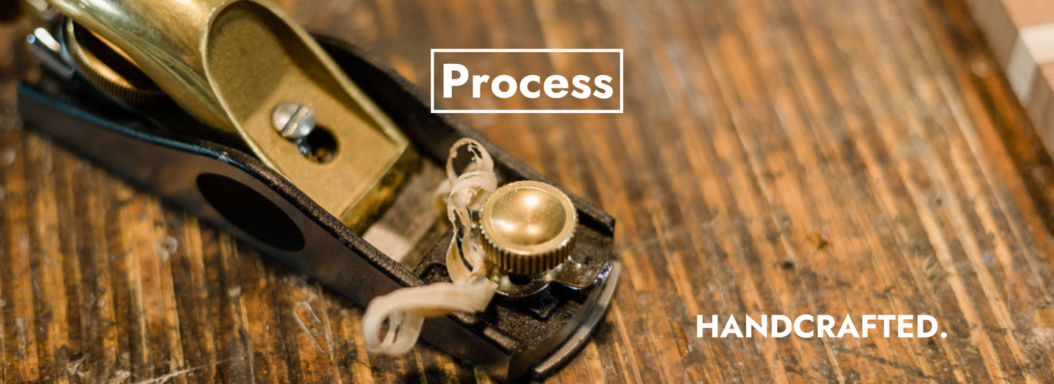 A handplane sits on a workbench at the Deviate Board Building shop with a fresh wood shaving sitting nearby.
